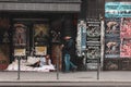 Homeless man on the sidewalk, laid down on a mat next to an abandoned building, with people walking by in downtown Bucharest