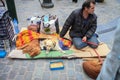 Homeless man with two dogs asks alms from passers-by sitting on the ground