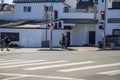 A homeless man wearing a black hoodie pushing a shopping cart and a man crossing a street wearing a black shirt and gray shorts Royalty Free Stock Photo