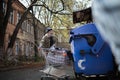 Homeless old man with shopping cart standing close to trash can. Royalty Free Stock Photo