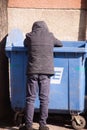 A homeless person leaned into a trash can in search of some food. (Uzhhgorod, Ukraine - March 8, 2021)