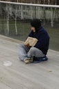 Homeless person sitting asking for charity. Royalty Free Stock Photo