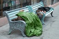 Homeless person is sleeping on a bench in a cold autumn day in a park in European union& x27;s poorest country Bulgaria