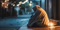 A homeless person wrapped in a blanket, sitting by the street side, casting a light on homelessness, concept of Royalty Free Stock Photo