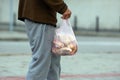 Homeless poor man walks down the city street with a bag in his hand. social problems of the city and people Royalty Free Stock Photo