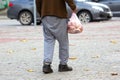 Homeless poor man walks down the city street with a bag in his hand. social problems of the city and people Royalty Free Stock Photo