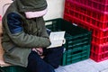 Homeless reading a book in front of a store in the winter, Bucharest, Romania, 2020