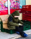 Homeless reading a book in front of a store in the winter, Bucharest, Romania, 2020