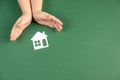 Homeless shelter and real estate concept. Close up of child hands holding white paper house and heart on green background. Royalty Free Stock Photo