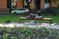 The homeless sleeps on a bench with a dog