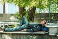 Homeless veteran. Poor hungry and tired homeless man ex military soldier sleep in the shade on the bench in urban city street soci Royalty Free Stock Photo