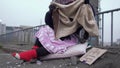 Homeless woman appreciate the shoes worn on a thick red sock and looks at the jacket appreciatively.