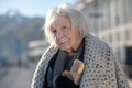 Homeless woman with coat on shoulders holding bread Royalty Free Stock Photo