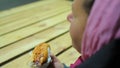 Homeless woman eating hot dog at charity event. Unhealthy and insalubrious food