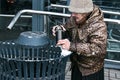 A homeless woman looking for food in a dumpster. Selective focus, street photo, urban