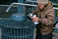 A homeless woman looking for food in a dumpster. Selective focus, street photo, urban
