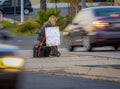 Homeless woman with sign on road median with blurred traffic Royalty Free Stock Photo