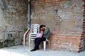 A homeless woman sleeping on a monoblock chair at the side of the brick wall in an old church yard Royalty Free Stock Photo