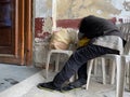 Homeless woman sleeping on a monoblock chair at the side of the wall in an old churchyard Royalty Free Stock Photo