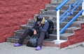 A homeless woman sleeps sitting on the stairs