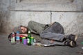 Homeless young alcohol addict lying drunk on street sidewalk in Berlin.