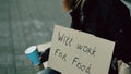 Homeless young man beg for money shaking cup to pay attention people walking near beggar at the city sidewalk