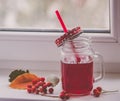 Bright red compote in the original glass mug, autumn composition on the window. Hugue style, autumn style, autumn still life Royalty Free Stock Photo