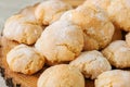 Homemade amaretti cookies on a wooden board on a white stone backdrop.