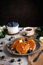 Homemade American pancakes with fresh blueberries, walnuts and honey on a plate. Healthy morning breakfast concept.