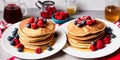 Homemade American pancakes with honey, caramel sauce or syrup with fresh blueberries, raspberries and strawberries on a