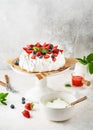 Homemade Anna Pavlova cake with fresh strawberries, blueberries, raspberries, vanilla cream and strawberry sauce. Royalty Free Stock Photo