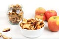 Homemade apple chips in a cup and a jar of apples on a white background, in the fall apples are baked in the oven or dryer for