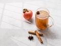 Homemade apple cider with apples and cinnamon in cup on a light background with fresh fruits, spices and shadows. The concept of Royalty Free Stock Photo