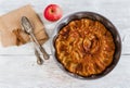 Homemade apple and cinnamon cake. Pie in baking dish, vintage fork and spoon and fresh fruit on wooden background. Top view