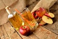 Homemade apple juice with ice, red apples, straw, still life on a wooden table