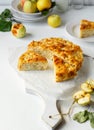 Homemade apple pie served on cutting board, yellow apples on white background