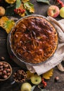 Homemade apple pie surrounded by fresh fruits, nuts, apples