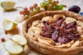 A homemade apple plums pie decorated with fresh apples, grapes, brown raisins and sesame on light wooden background Royalty Free Stock Photo