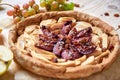 A homemade apple plums pie decorated with fresh apples, grapes, brown raisins and sesame on light wooden background Royalty Free Stock Photo