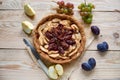 A homemade apple plums pie decorated with fresh grapes, plums, brown raisins, sesame and silver vintage knife on the wooden table Royalty Free Stock Photo