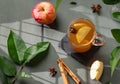 Homemade apple punch with fresh apples, cinnamon and spices in cup on a green background with fresh fruits, branch and morning