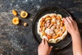 Homemade apricot galette made with fresh organic apricotes on wooden table, top view. Process of baking. Making dought. Hands with