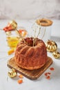 Homemade autumn carrot or pumpkin bundt cake with candied fruits, cup of tea and golden decorative pumpkins on light background