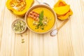 Homemade autumn hot pumpkin cream soup with smocked bacon and seeds. Raw pumpkin, fresh chives, dill, salt in spoon on wooden Royalty Free Stock Photo