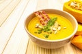 Homemade autumn hot pumpkin cream soup with smocked bacon and seeds. Raw pumpkin, fresh chives, dill, salt in spoon on wooden Royalty Free Stock Photo