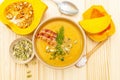 Homemade autumn hot pumpkin cream soup with smocked bacon and seeds. Raw pumpkin, fresh chives, dill, salt in spoon on wooden Royalty Free Stock Photo