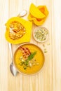 Homemade autumn hot pumpkin cream soup with smocked bacon and seeds. Raw pumpkin, fresh chives, dill, salt in spoon on wooden Royalty Free Stock Photo