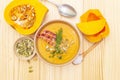 Homemade autumn hot pumpkin cream soup with smocked bacon and seeds. Raw pumpkin, fresh chives, dill, salt in spoon on wooden Royalty Free Stock Photo