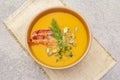 Homemade autumn hot pumpkin cream soup with smocked bacon and seeds. Raw pumpkin, fresh chives, dill, vintage linen cloth on stone Royalty Free Stock Photo