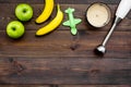 Homemade baby food. Cook puree with apple and banana with immersion blender. Dark wooden background with toy top view Royalty Free Stock Photo